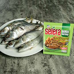 Piring berisi ikan segar dan kemasan Selera Bumbu Goreng Serbaguna dari Kobe ukuran 70g