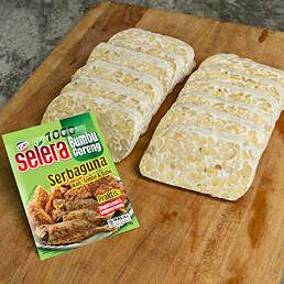 Talenan berisi potongan tempe dan kemasan Selera Bumbu Goreng Serbaguna dari Kobe