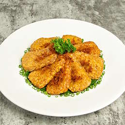 Tempe goreng berbumbu Selera Bumbu Goreng Serbaguna disajikan di piring putih dengan taburan bawang goreng dan irisan daun bawang